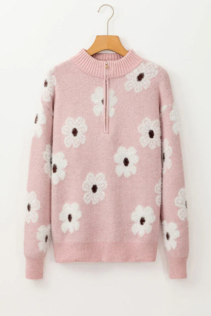 Pink knit sweater with white floral pattern and front zip collar, displayed on hanger