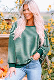 Woman wearing green and white striped sweater with relaxed fit and casual jeans in a sunflower garden