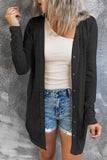 Woman wearing a black button-down cardigan over a beige ribbed tank top and denim shorts