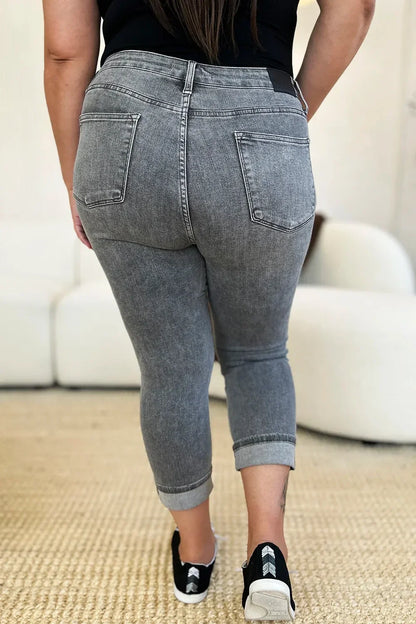 Back view of woman in grey cropped skinny jeans with rolled cuffs, casual setting