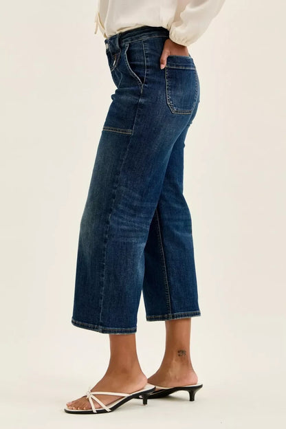 Woman wearing cropped wide leg dark wash jeans with white heeled sandals