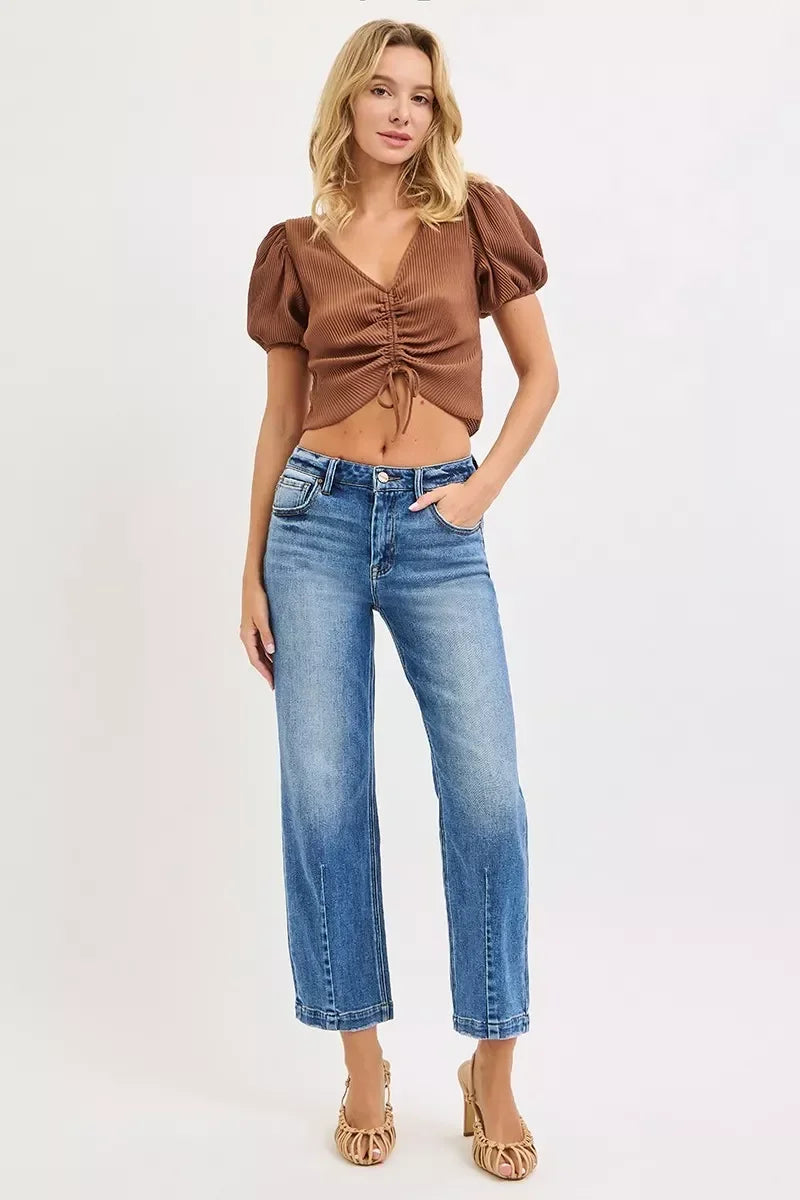 Woman in a brown ruched short-sleeve top and blue high-waisted straight jeans