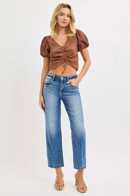 Woman in a brown ruched short-sleeve top and blue high-waisted straight jeans