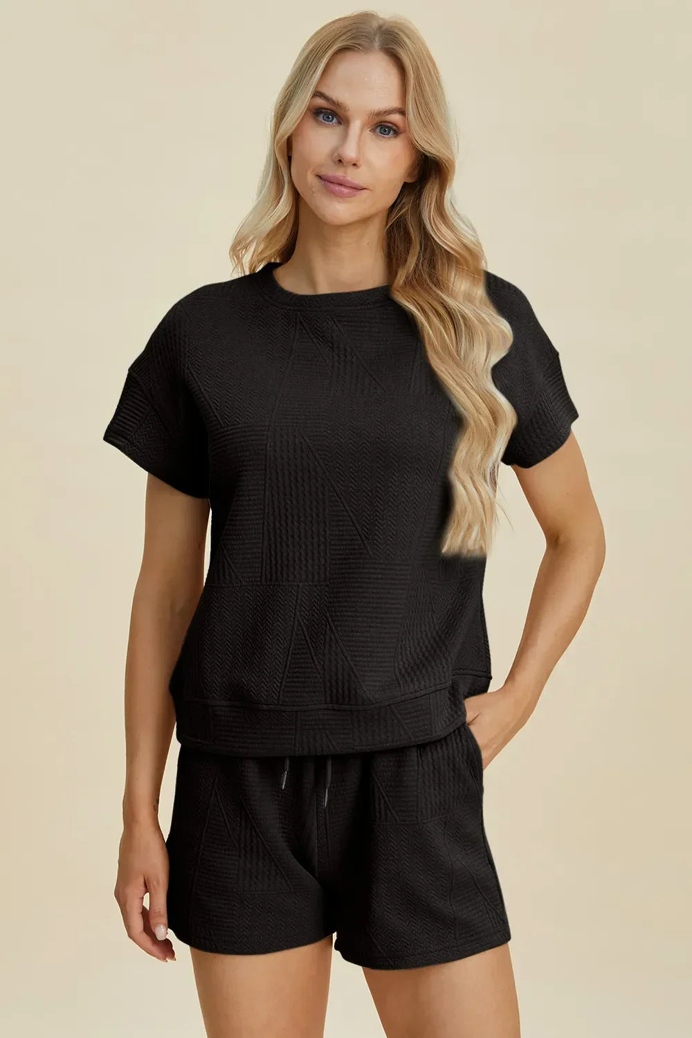 Woman wearing black textured short sleeve lounge set with relaxed fit and shorts