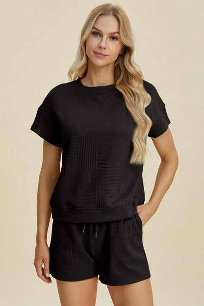 Woman wearing black textured short sleeve lounge set with relaxed fit and shorts
