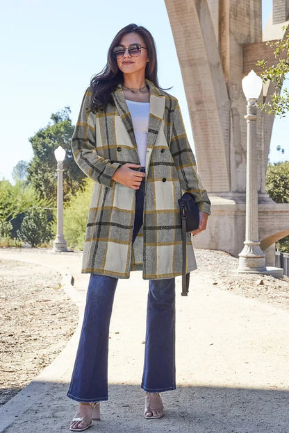 Woman wearing a long plaid coat, white top, blue jeans, and heels outdoors