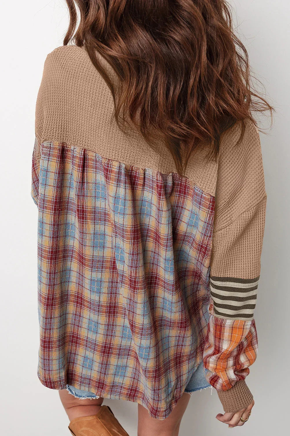 Woman wearing a relaxed, colorblock plaid and waffle knit long sleeve top with denim shorts