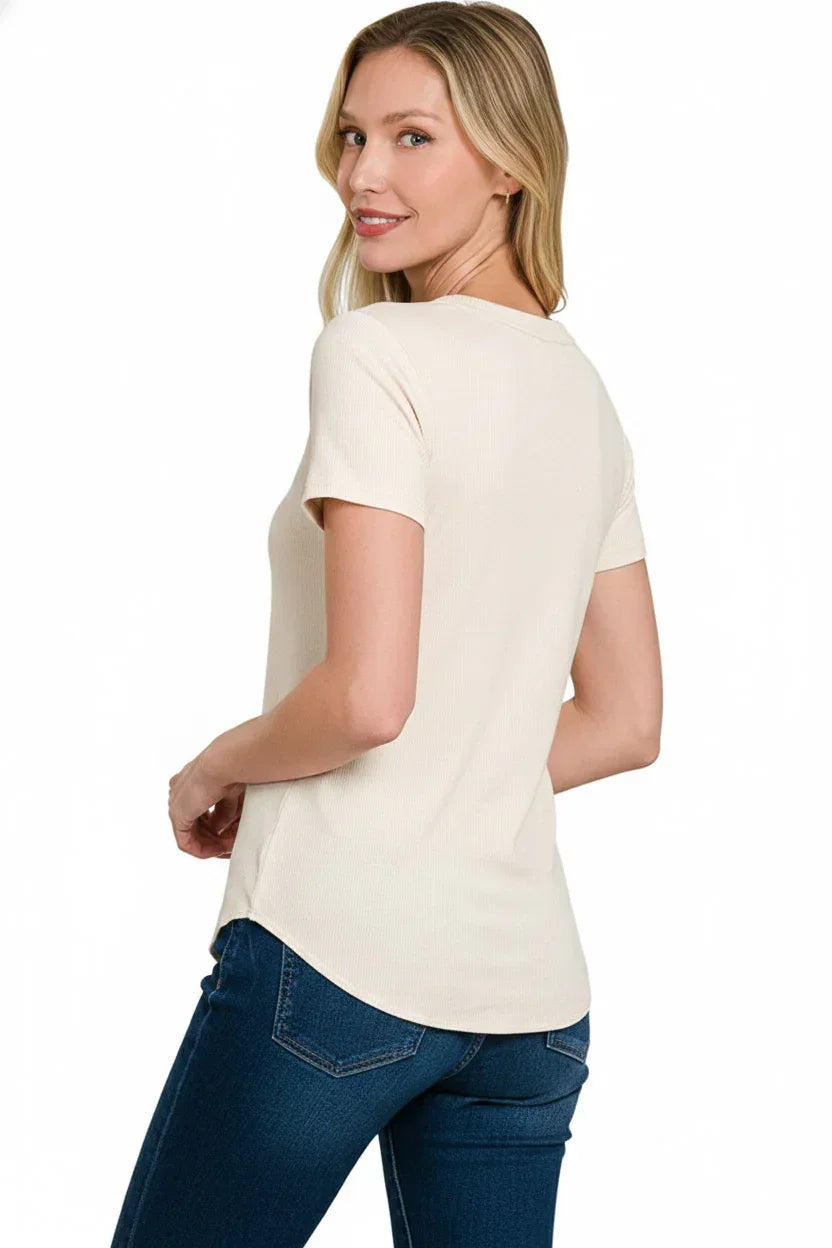 Woman wearing a short sleeve cream knit top and blue jeans, photographed from the back.