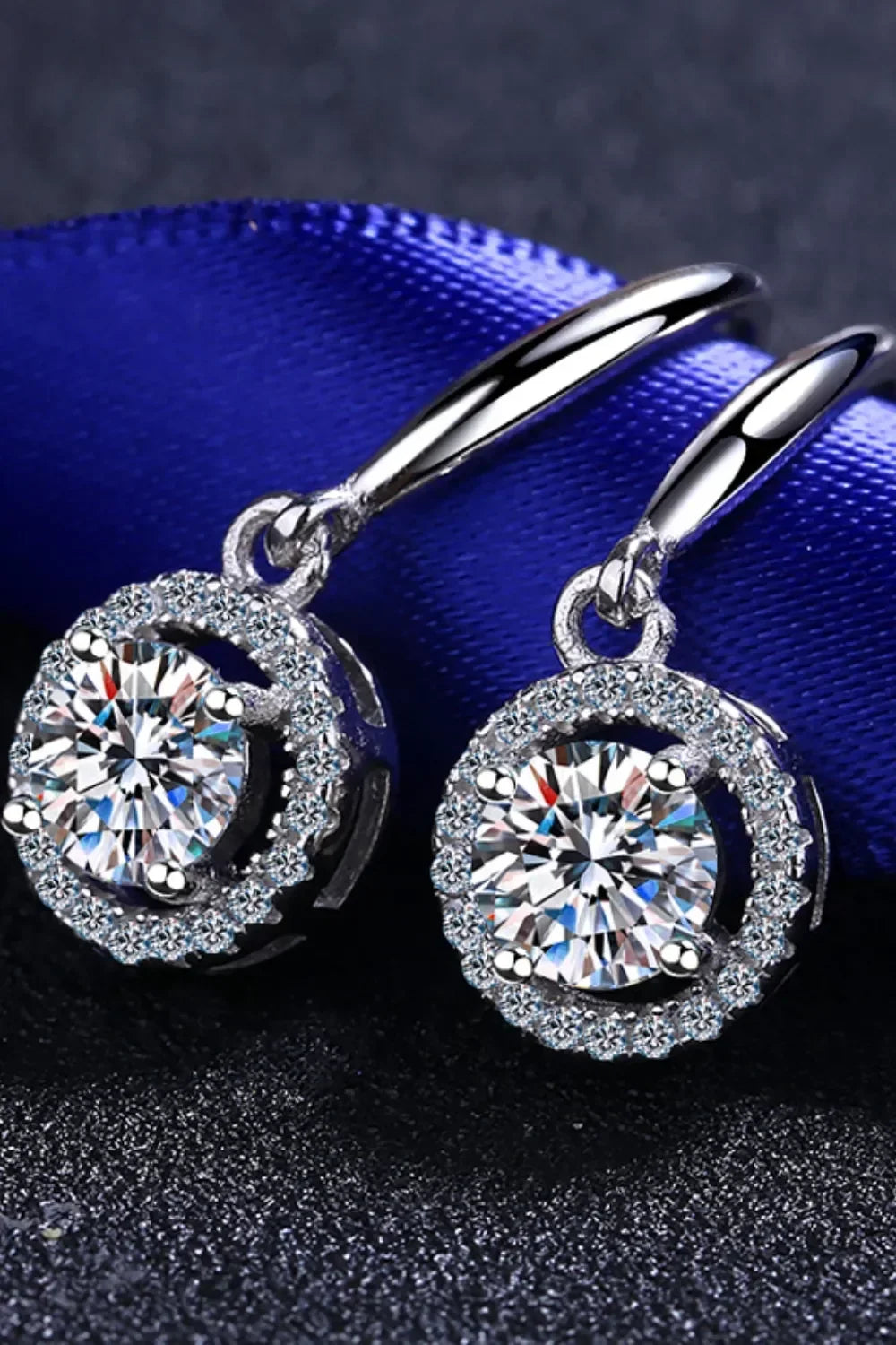 Elegant silver drop earrings with round cut clear crystals and pavé accents on dark background