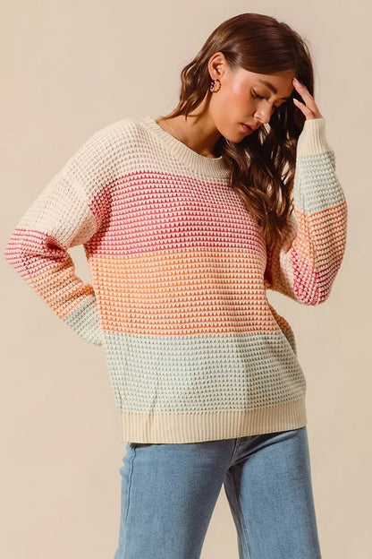 Woman wearing a pastel colorblock knit sweater with relaxed fit and blue jeans