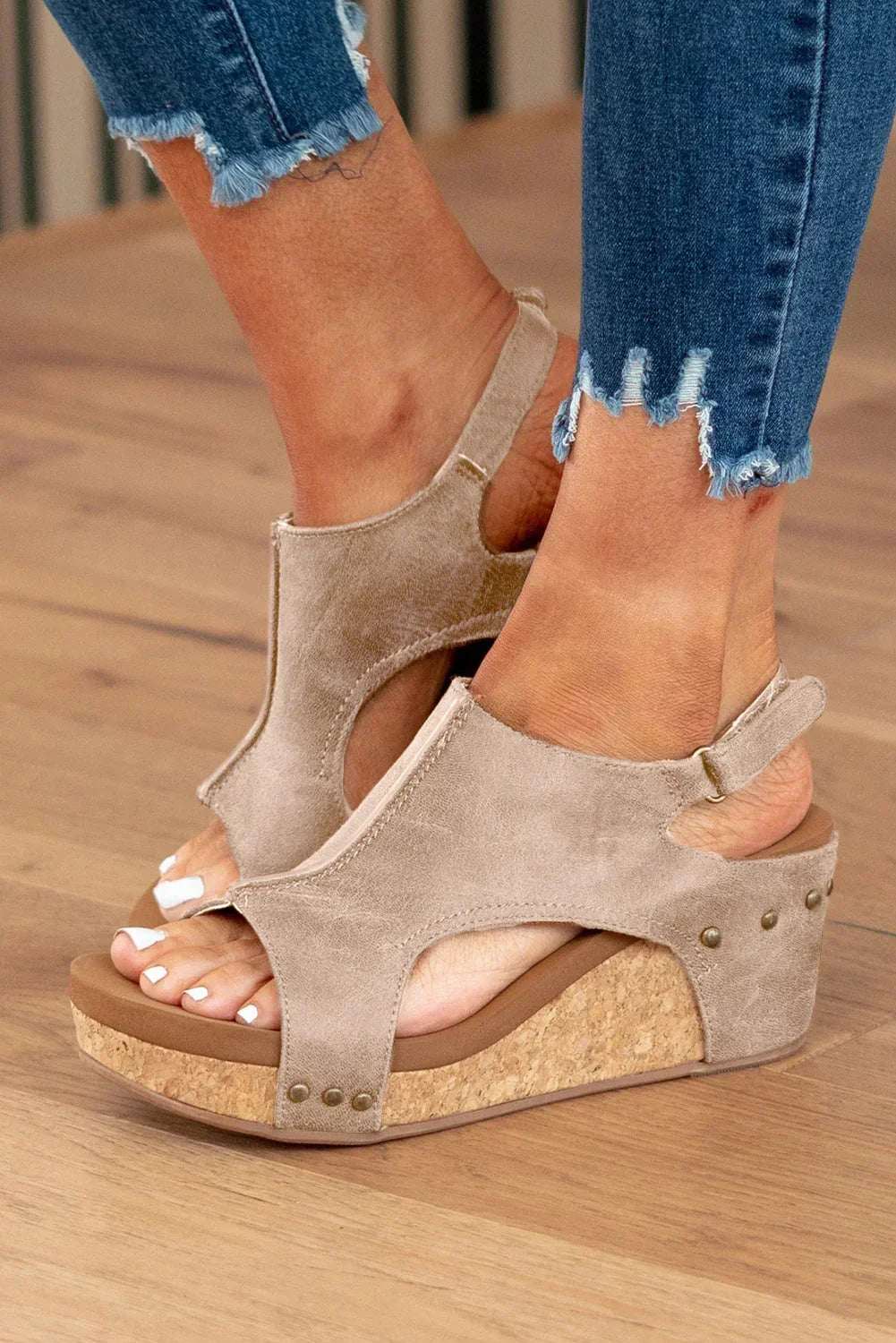 Taupe wedge sandals with cork soles, worn with frayed hem skinny jeans on wood floor