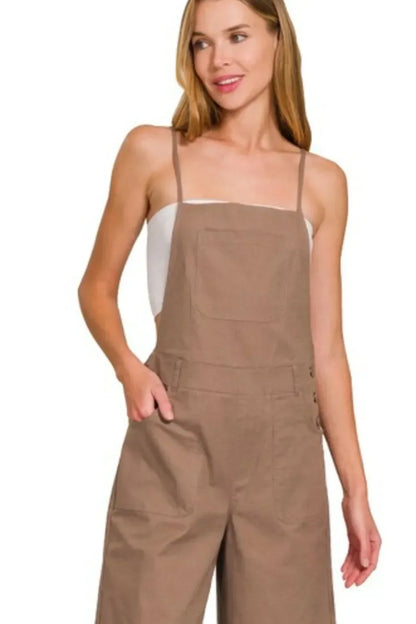 Woman wearing taupe wide-leg overalls with front pocket and thin straps, casual style
