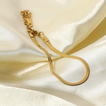 Gold herringbone chain bracelet on ivory satin fabric, minimalist jewelry style