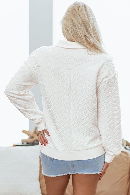 Woman wearing quilted white long sleeve top and light denim shorts indoors