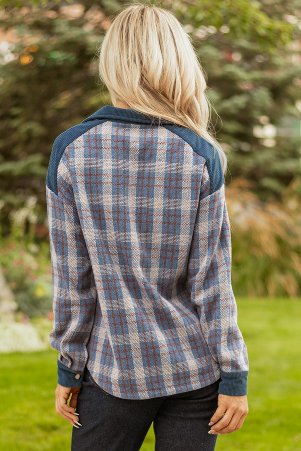 Woman outdoors wearing blue plaid long-sleeve shirt with dark shoulder accents
