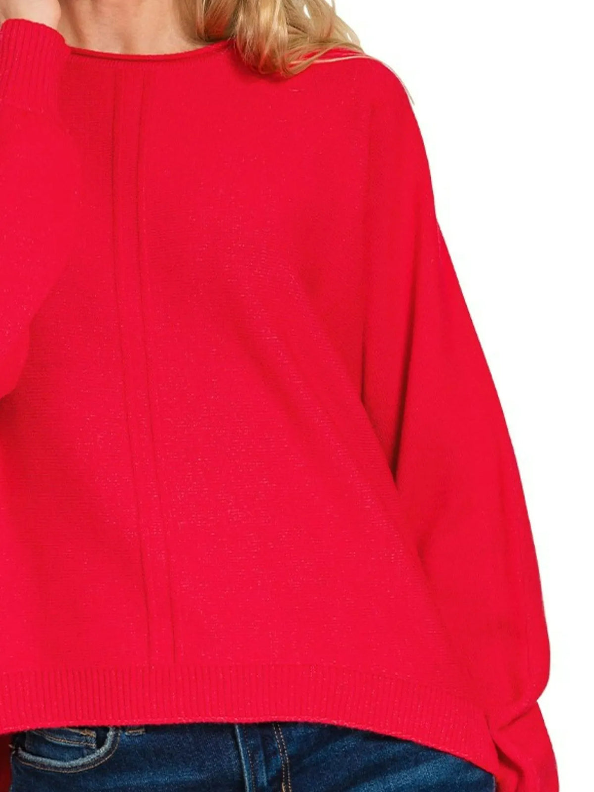 Woman wearing a bright red relaxed-fit sweater with blue jeans, front seam detail visible