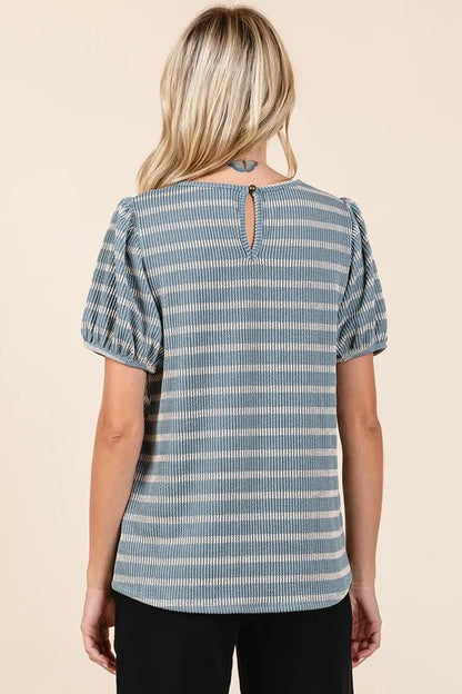 Back view of a woman wearing a blue and white striped short sleeve blouse with keyhole detail.