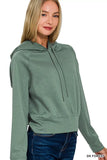 Woman wearing a dark forest green hooded sweatshirt with long sleeves and blue jeans
