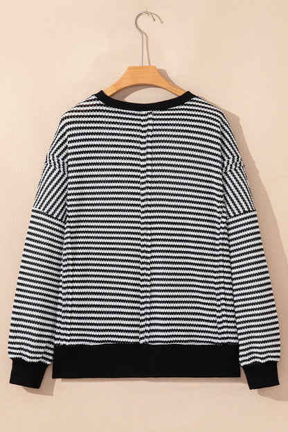 Black and white striped knit sweater with dropped shoulders and ribbed cuffs, back view