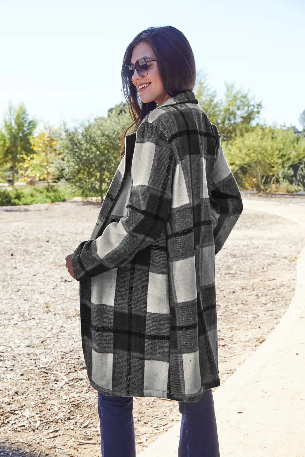 Woman outdoors wearing a black and white plaid coat and sunglasses