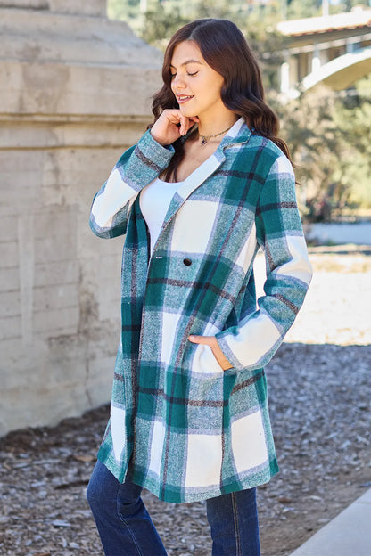 Woman wearing a teal and white plaid coat over a white top and jeans outdoors