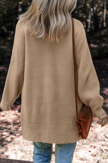 Woman outdoors wearing beige textured sweater, blue jeans, and brown crossbody bag