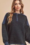 Woman wearing a textured dark knit pullover with blue button collar and shoulder accents
