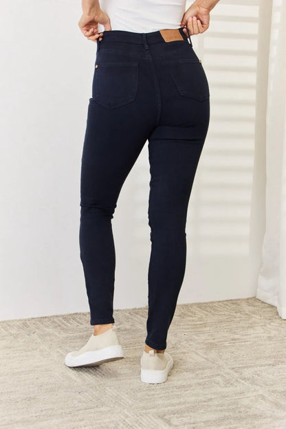 Woman wearing dark blue high-waisted skinny jeans and white sneakers indoors