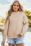 Woman outdoors wearing a beige long sleeve pullover and light denim shorts