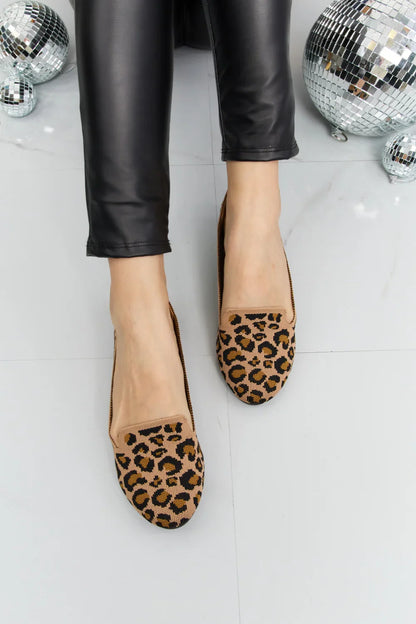 Leopard print flats paired with black faux leather pants, disco balls on floor
