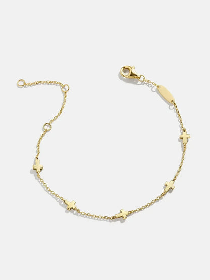 Delicate gold chain bracelet with small cross charms and a lobster clasp on white background