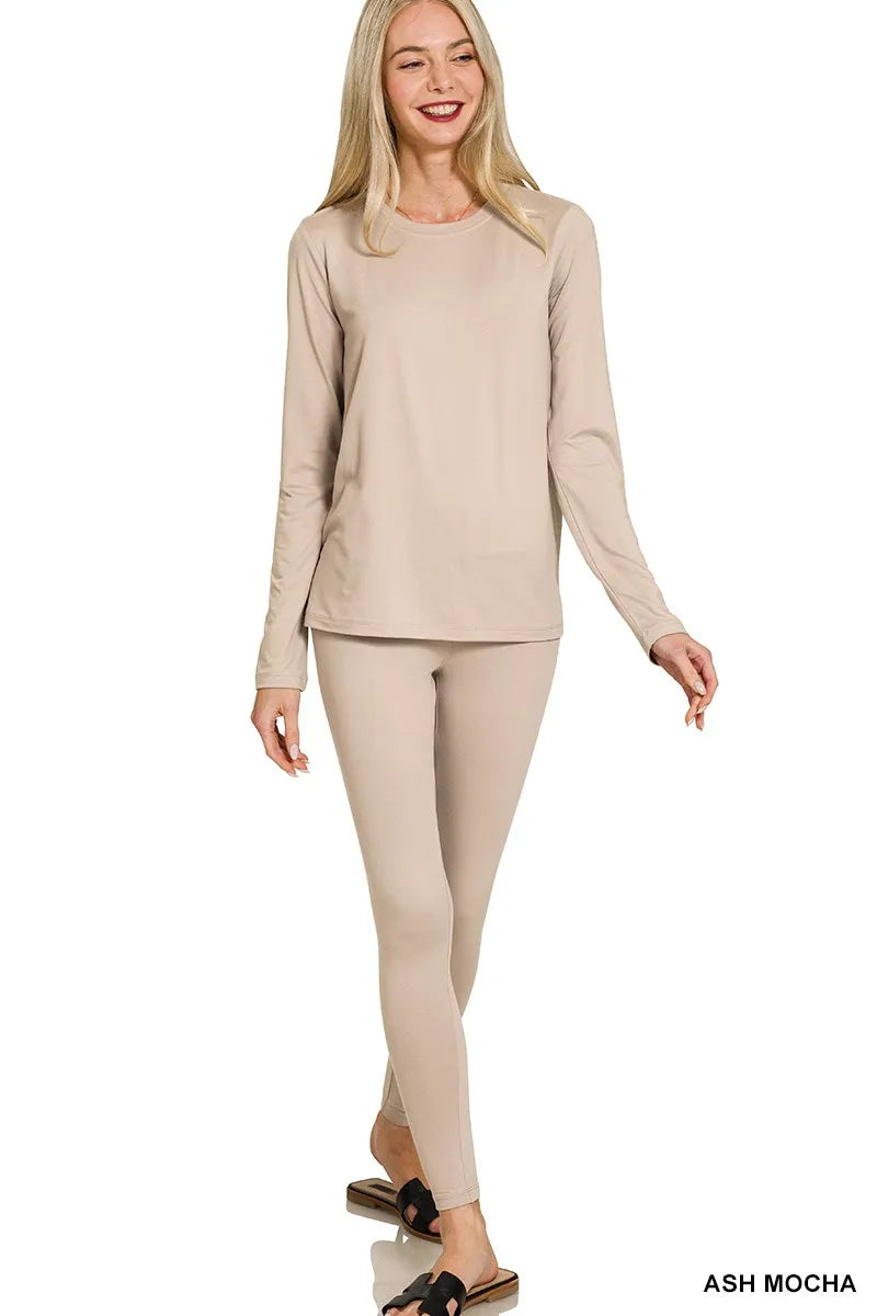 Woman wearing a beige long-sleeve top and leggings on a white background