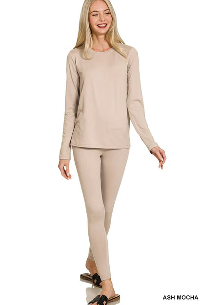 Woman wearing a beige long-sleeve top and leggings on a white background