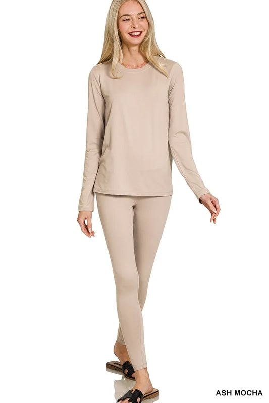 Woman wearing a beige long-sleeve top and leggings on a white background