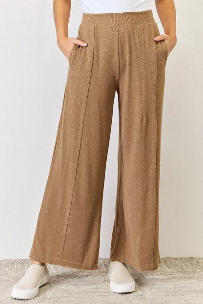 Woman wearing relaxed fit, wide leg brown knit pants with side pockets and white shoes