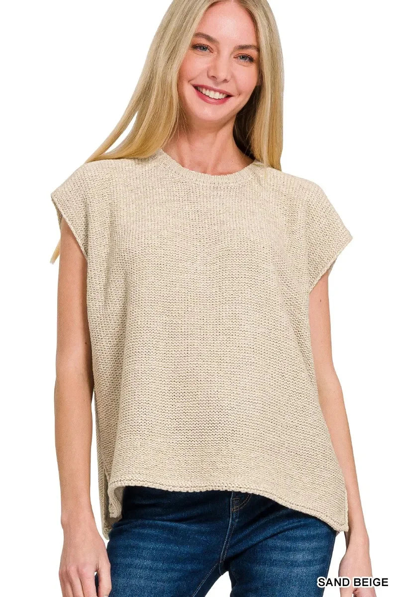 Woman wearing a sleeveless sand beige knit top with relaxed silhouette and crew neckline.