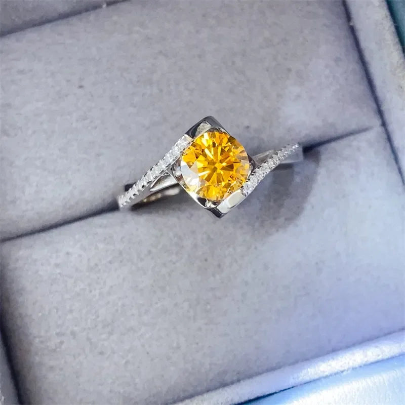 Silver ring with yellow gemstone center and small clear stones in a gray jewelry box