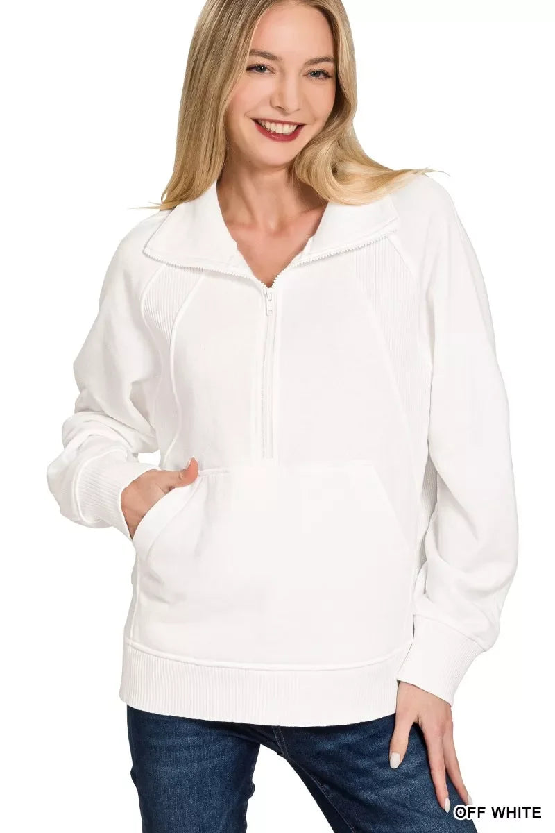 Woman wearing an off-white quarter-zip pullover with kangaroo pocket and relaxed fit