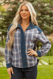Woman wearing a blue plaid zip-up jacket with dark jeans, standing outdoors in a garden.