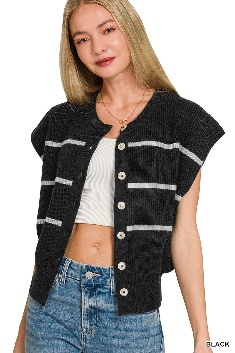 Woman wearing a black short sleeve button-up knit cardigan with white stripes, white ribbed crop top, and blue jeans.