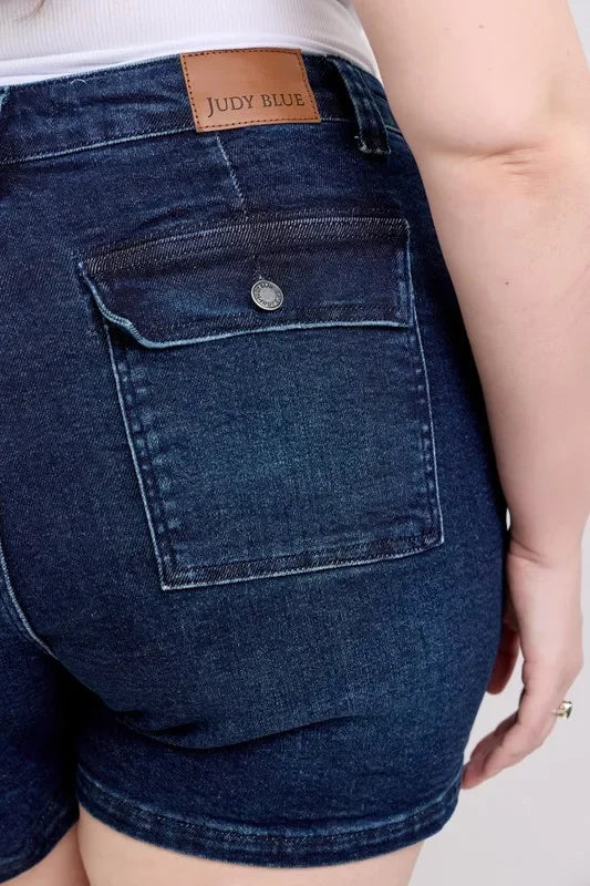 Close-up of dark wash denim shorts with back pocket and leather label detail