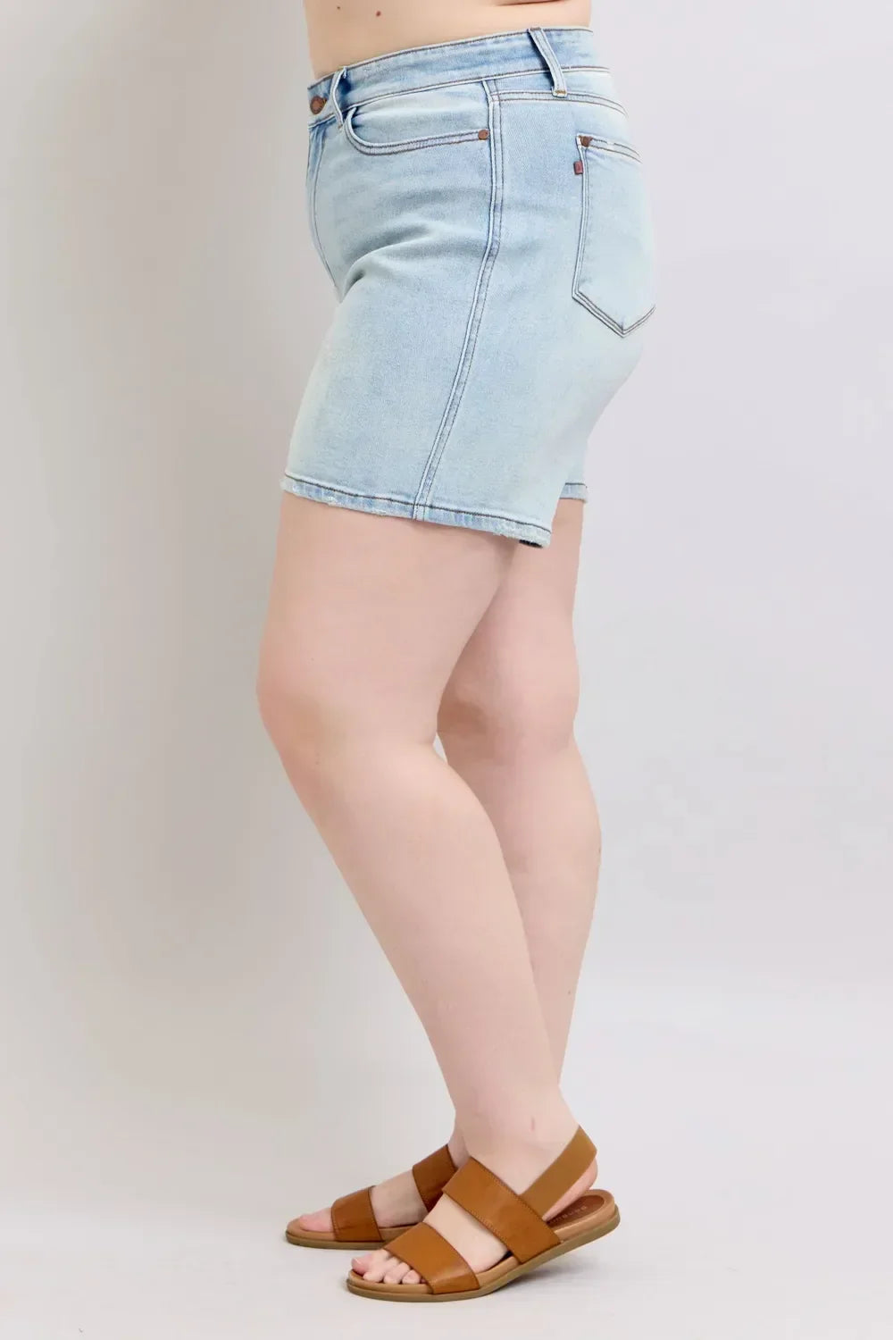 Light wash denim shorts paired with tan flat sandals, side view on model