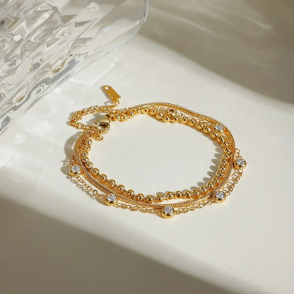 Gold layered bracelet with delicate chains and clear crystal accents on a neutral surface