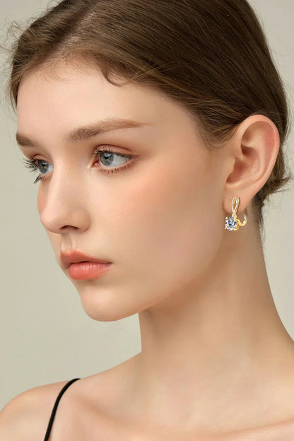 Woman wearing gold hoop earrings with crystal accent, minimalist style, neutral background