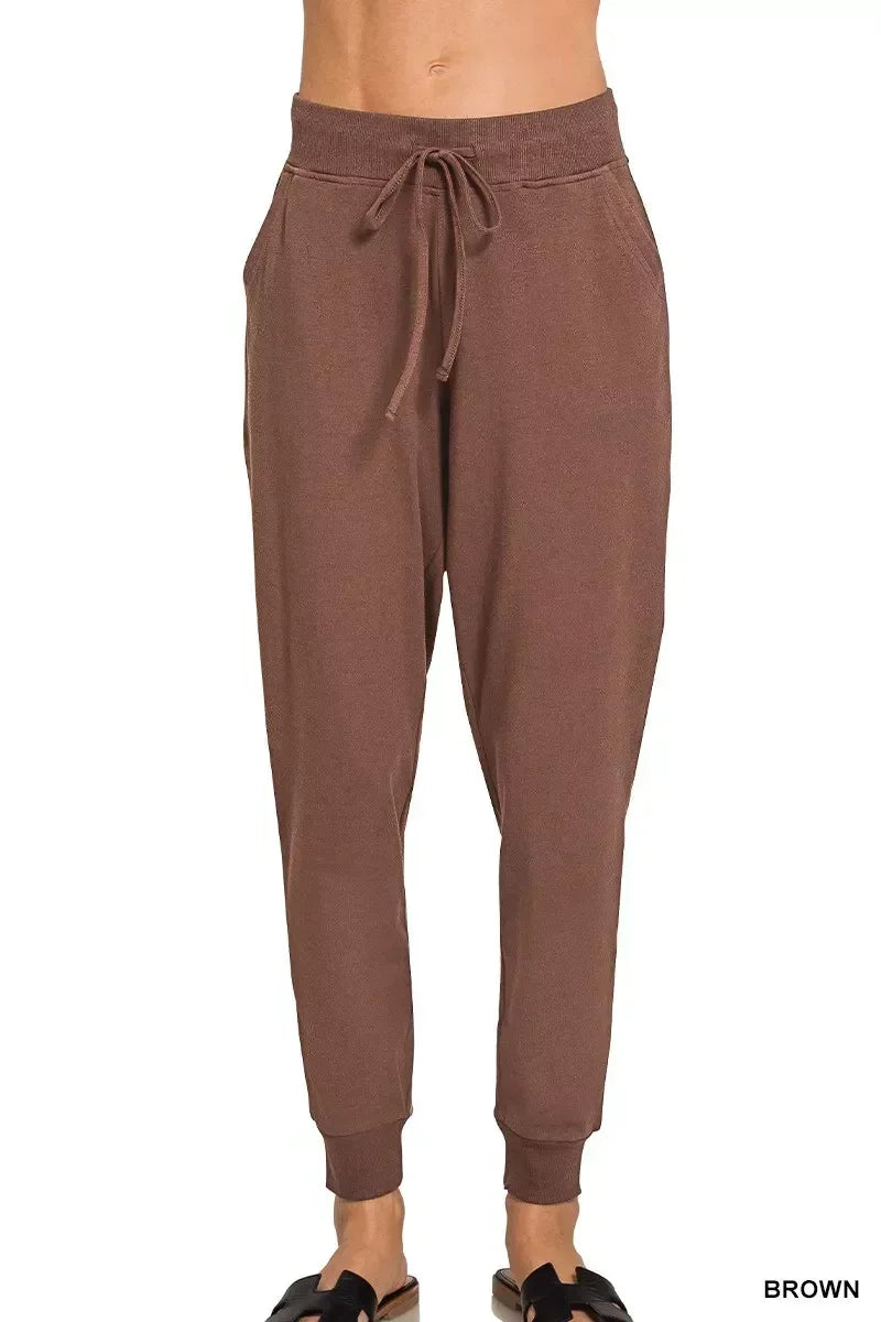 Brown women’s jogger pants with drawstring waist and relaxed fit, styled with slide sandals