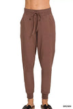 Brown women’s jogger pants with drawstring waist and relaxed fit, styled with slide sandals