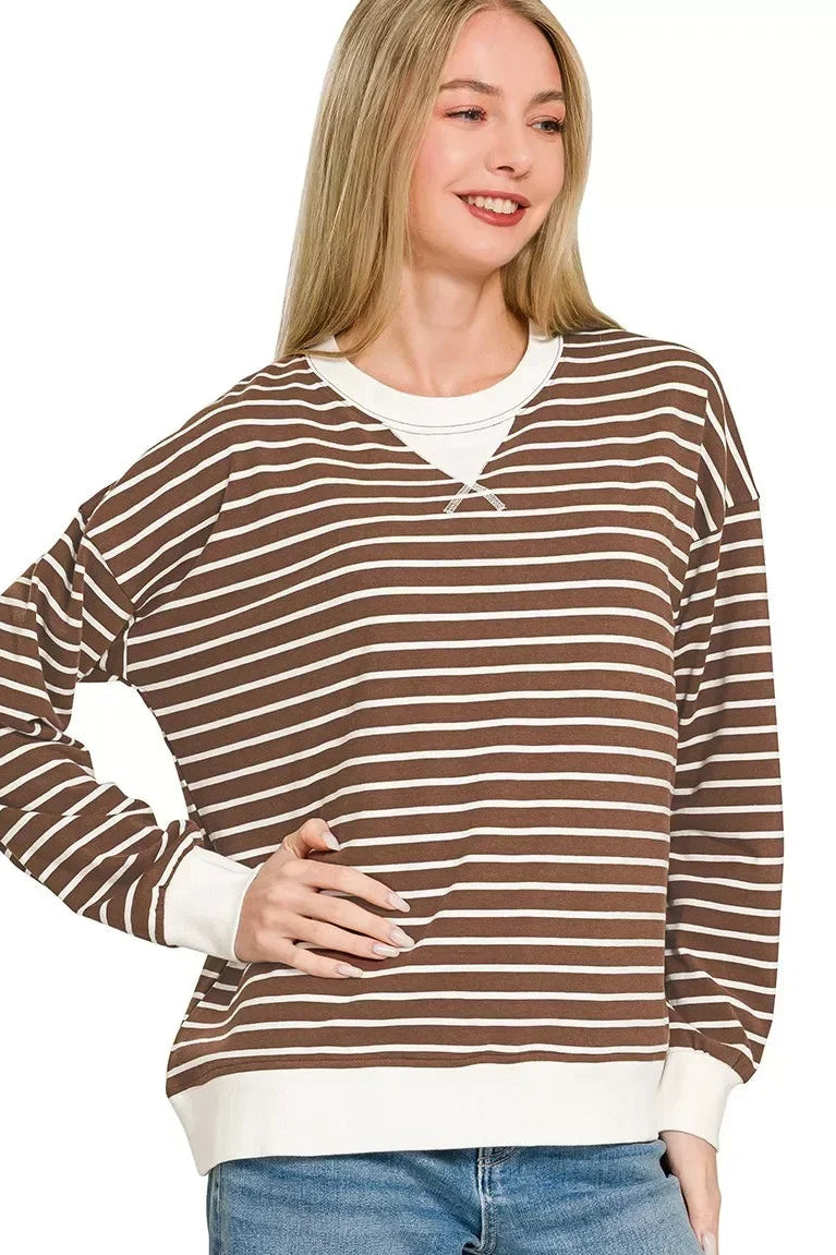 Woman wearing a brown and white striped long sleeve pullover with relaxed fit and white cuffs.