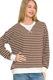 Woman wearing a brown and white striped long sleeve pullover with relaxed fit and white cuffs.