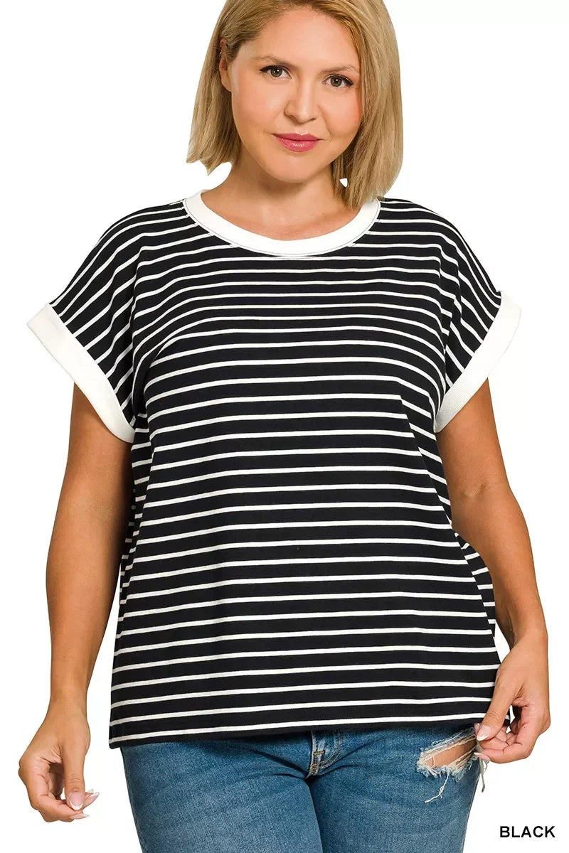 Woman wearing a black and white striped short sleeve top with white trim and blue jeans.