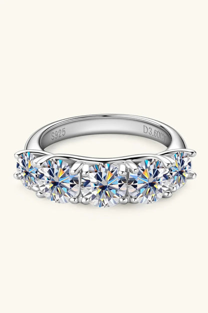 Sterling silver band ring with seven round-cut clear gemstones in prong settings.